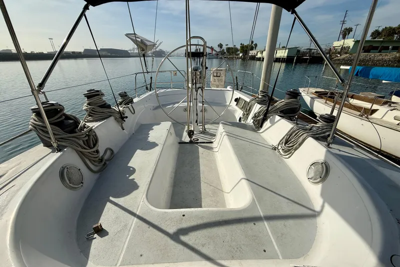 1985 MacGregor 65 sailboat cockpit with steering wheel, docked in a marina.