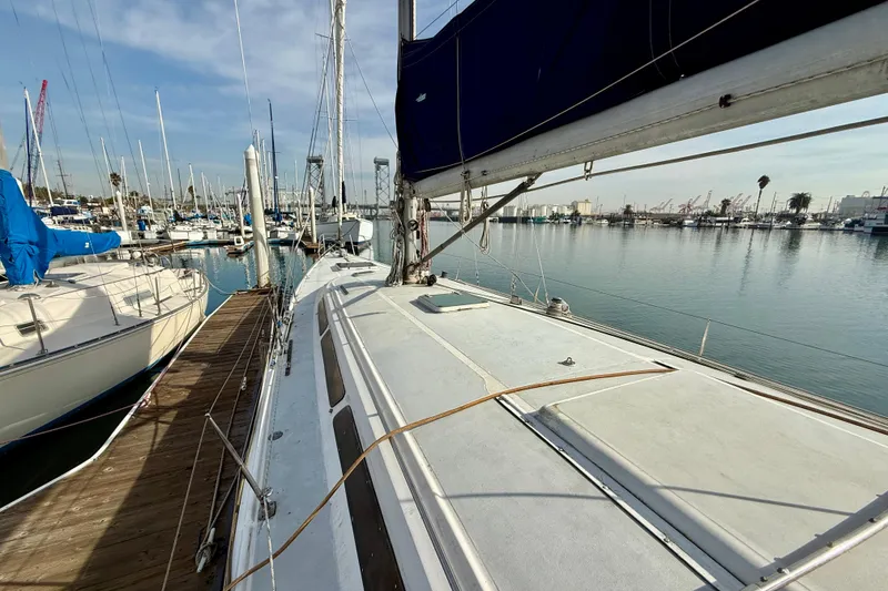 1985 MacGregor 65 sailboat docked in a marina, surrounded by other boats.