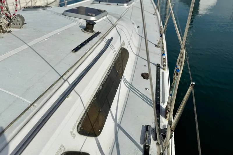 1985 MacGregor 65 sailboat deck with rigging and fittings, docked on calm water.