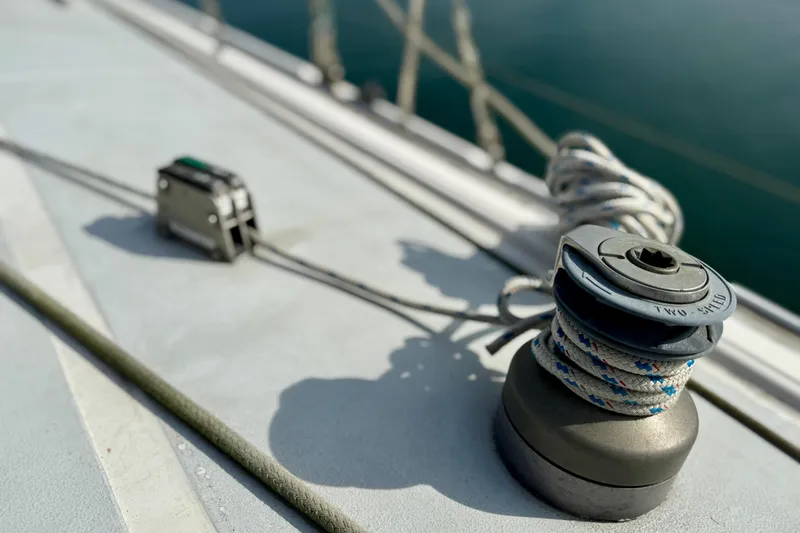 Winch and rope on 1985 MacGregor 65 sailboat deck, close-up view.