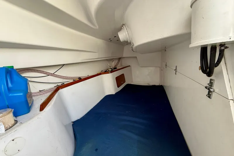 Interior of a 1985 MacGregor 65 sailboat, featuring storage space and blue flooring.