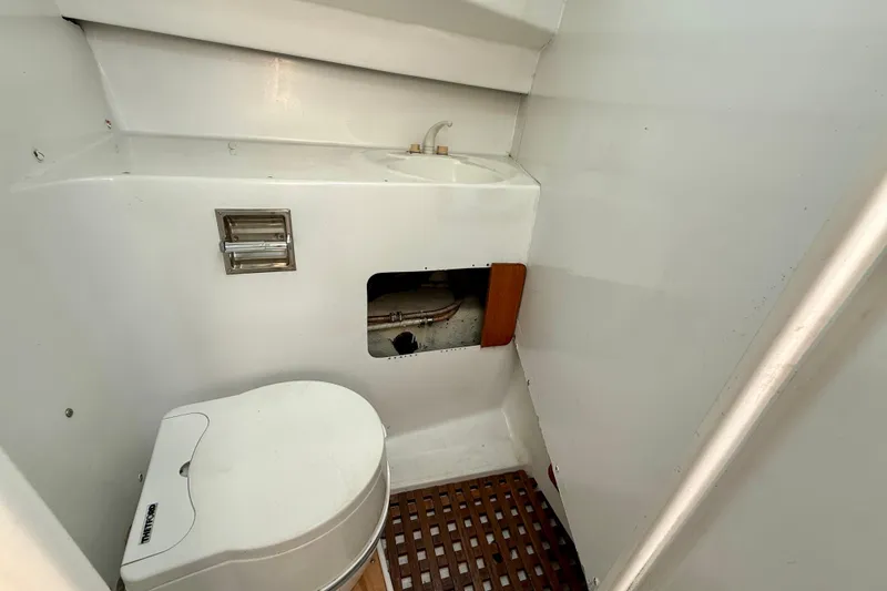 1985 MacGregor 65 yacht bathroom with toilet, sink, and wooden floor grate.