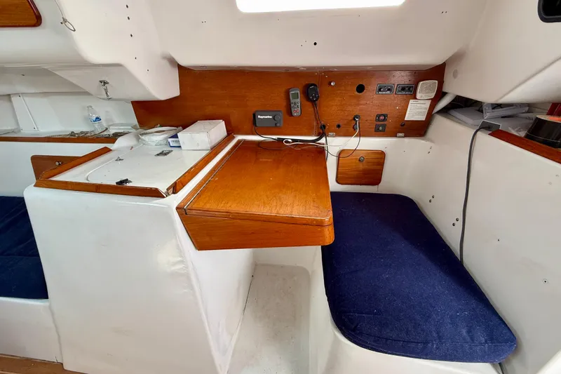Interior of 1985 MacGregor 65 sailboat with wooden table and blue seating.