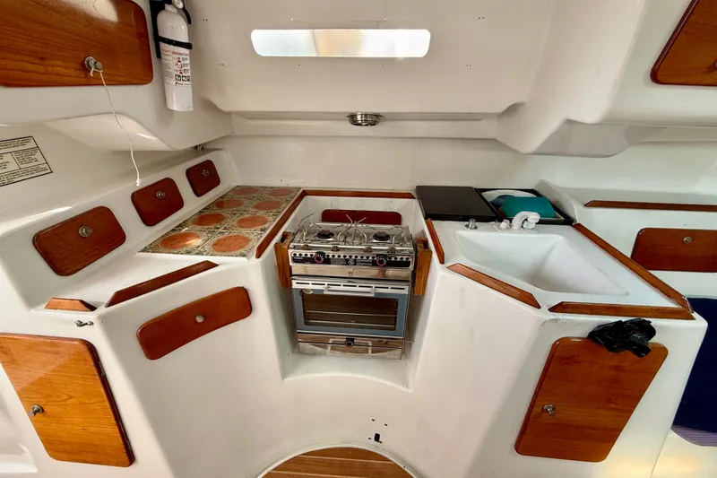 1985 MacGregor 65 yacht kitchen with stove, sink, and wooden cabinets.