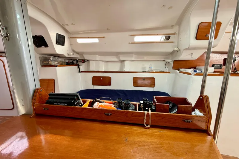 Interior of a 1985 MacGregor 65 sailboat with navigation equipment and cozy sleeping area.