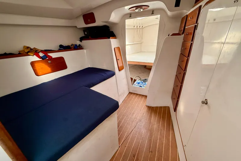 Interior of a 1985 MacGregor 65 sailboat with blue cushions and wooden accents.