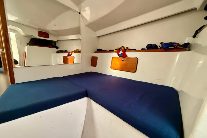 Interior cabin of 1985 MacGregor 65 sailboat with blue cushions and wooden accents.