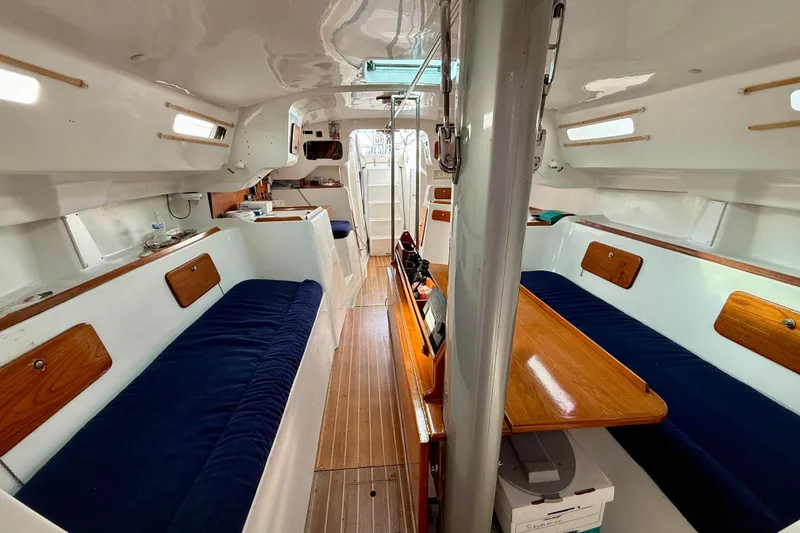 Interior of a 1985 MacGregor 65 sailboat with blue seating and wooden accents.