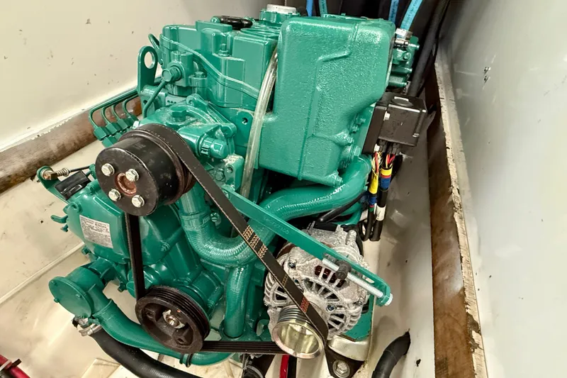 Engine of a 1985 MacGregor 65 sailboat, featuring a green motor and belt system.