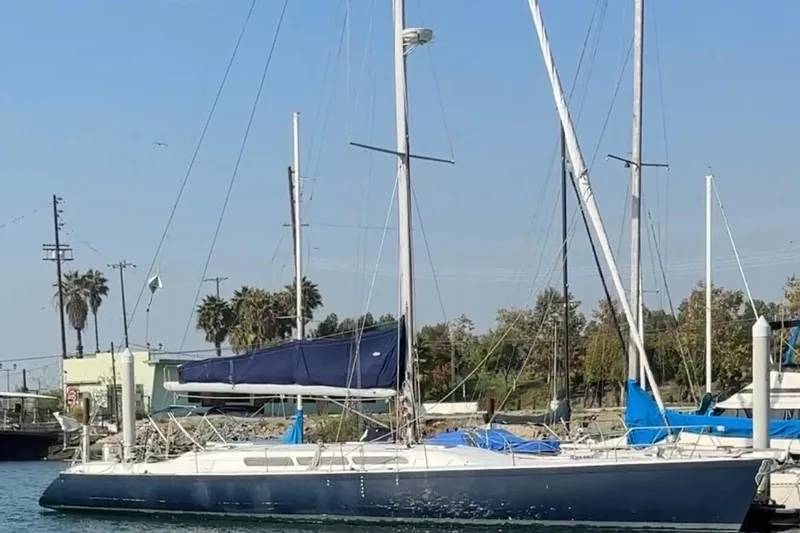 1985 MacGregor 65 sailboat docked, featuring blue sails and a sleek design.