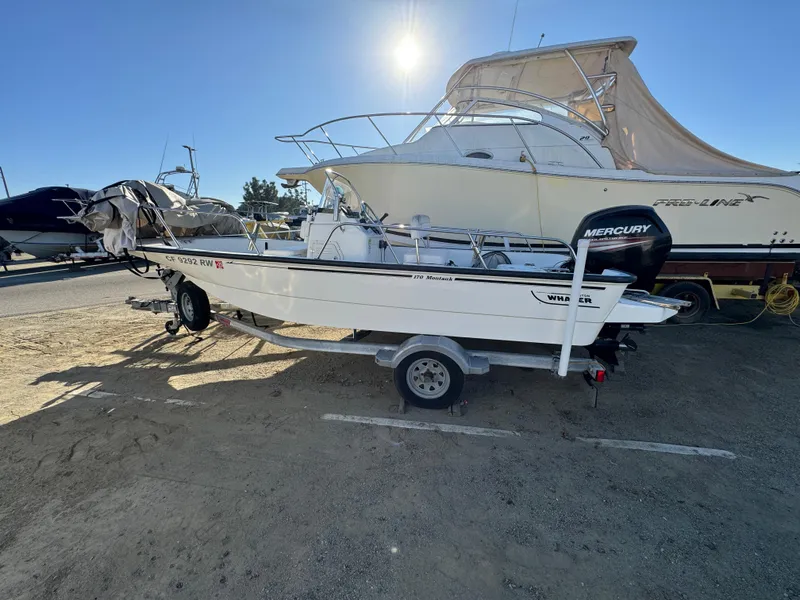 2016 Boston Whaler 170 MONTUCK boat on trailer, parked outdoors, with Mercury outboard motor.