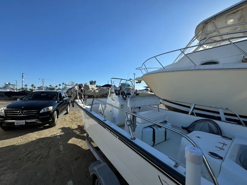 2016 Boston Whaler 170 MONTUCK boat parked beside a car in a marina.