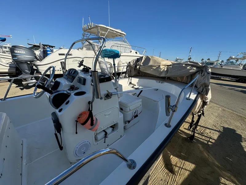 2016 Boston Whaler 170 MONTUCK boat with covered seating, docked under clear blue sky.
