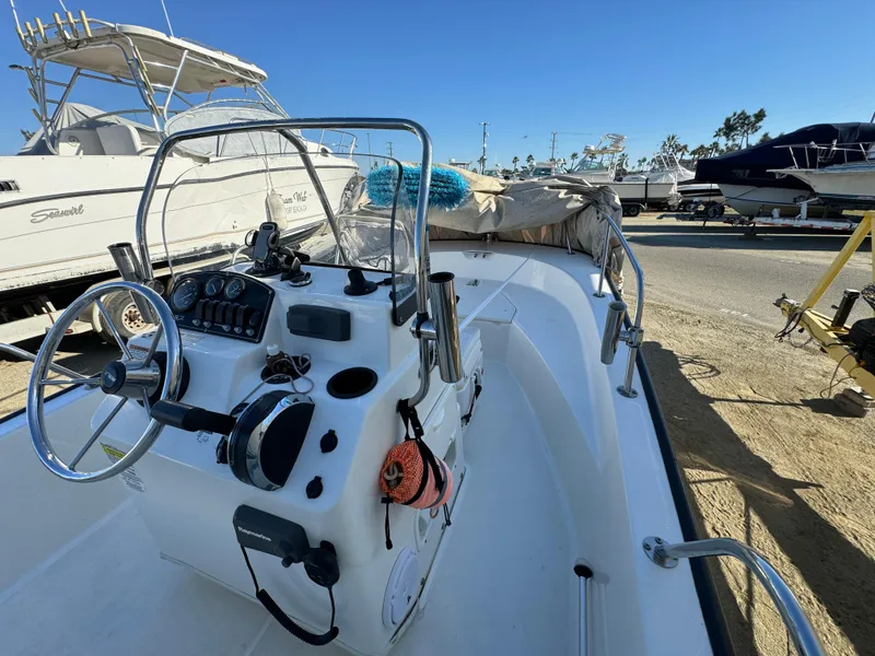 2016 Boston Whaler 170 MONTUCK boat with steering console, docked under clear blue sky.
