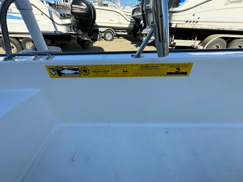 2016 Boston Whaler 170 MONTUCK boat interior with safety label, docked near other boats.