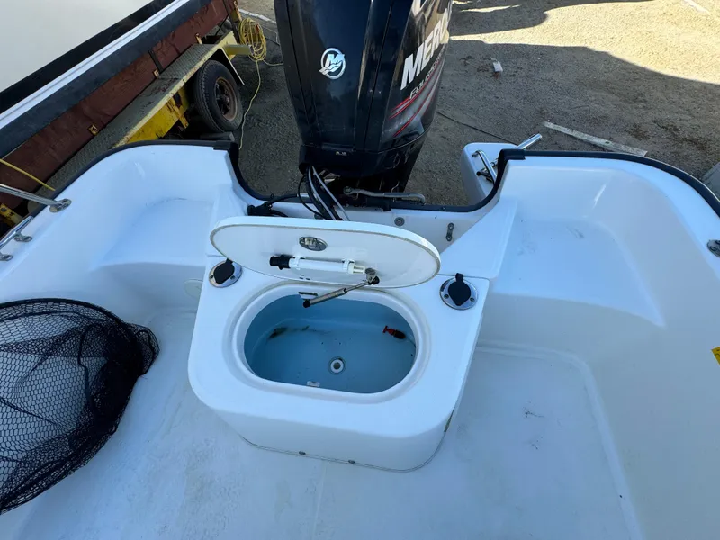 2016 Boston Whaler 170 MONTUCK boat with open storage compartment and Mercury outboard motor.