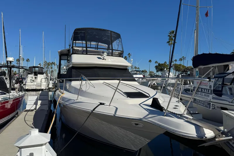1990 Sea Ray 380 Aft Cabin yacht docked, for sale sign visible, clear blue sky.