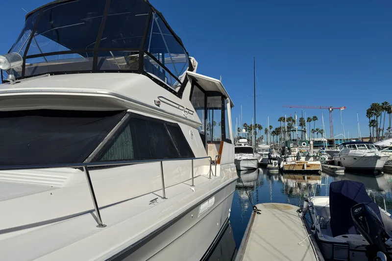 1990 Sea Ray 380 Aft Cabin yacht docked in a marina under clear blue skies.