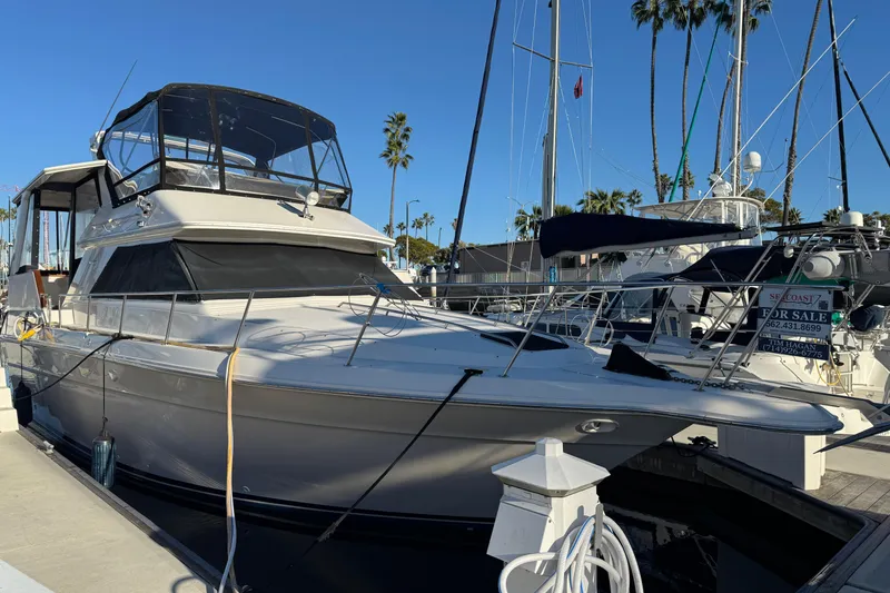1990 Sea Ray 380 Aft Cabin yacht docked, for sale, with clear blue sky background.