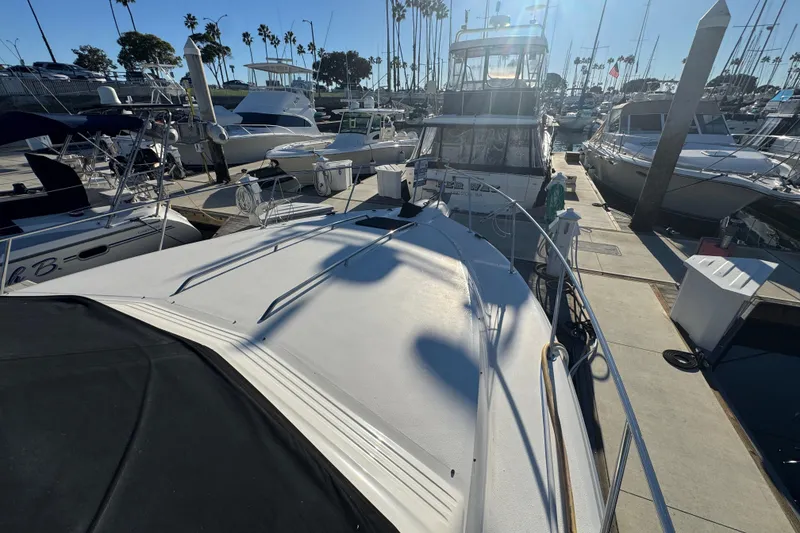 1990 Sea Ray 380 Aft Cabin yacht docked at marina under clear blue sky.