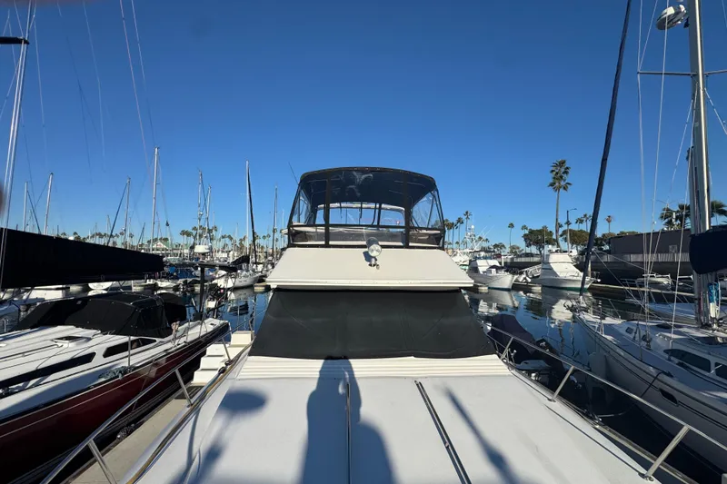 1990 Sea Ray 380 Aft Cabin yacht docked in a marina under clear blue skies.