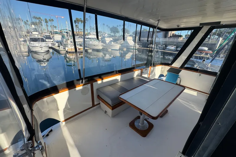 1990 Sea Ray 380 Aft Cabin yacht interior with marina view, featuring seating and table.