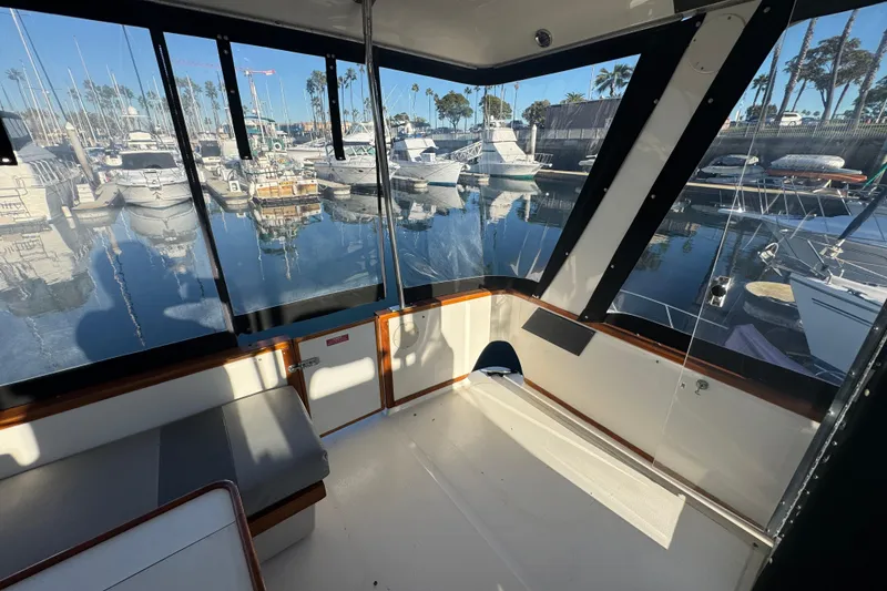 1990 Sea Ray 380 Aft Cabin interior with marina view, featuring seating and windows.