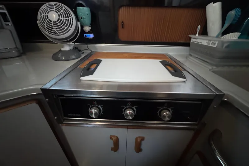 1990 Sea Ray 380 Aft Cabin kitchen with stove, cutting board, and fan.