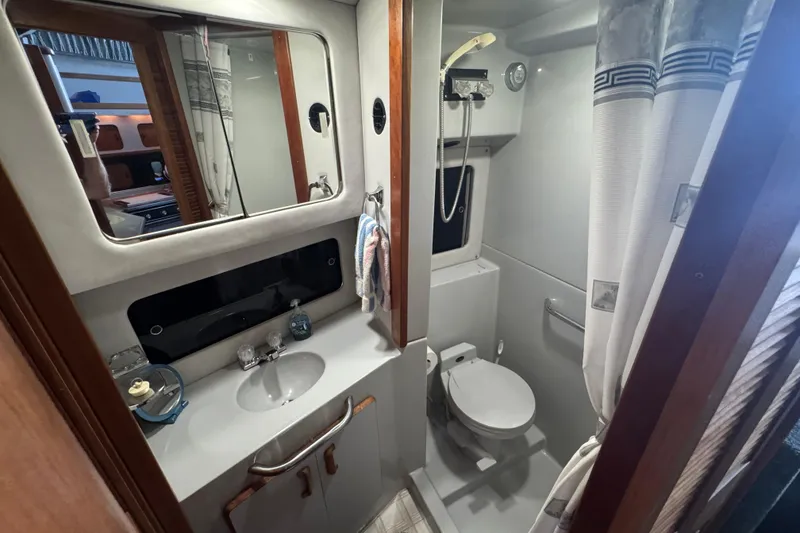 1990 Sea Ray 380 Aft Cabin bathroom with sink, mirror, and shower.