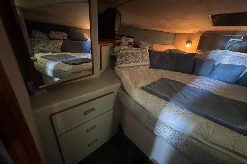 Cozy bedroom in 1990 Sea Ray 380 Aft Cabin yacht with mirror and soft lighting.