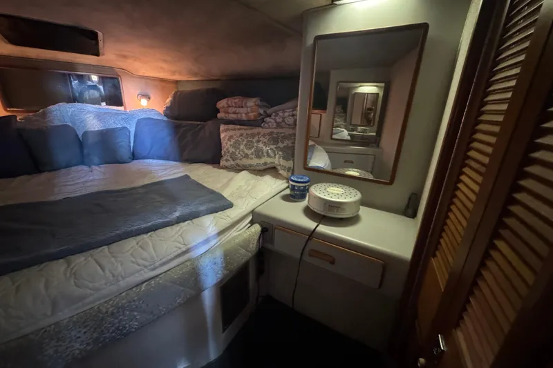 Cozy cabin interior of 1990 Sea Ray 380 Aft Cabin with bed and mirror.