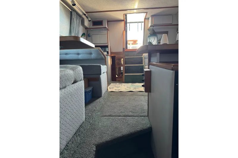 Interior of 1990 Sea Ray 380 Aft Cabin yacht, featuring cozy seating and carpeted flooring.