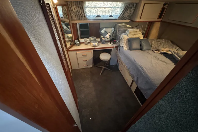 Cozy bedroom in 1990 Sea Ray 380 Aft Cabin with bed, desk, and decor.