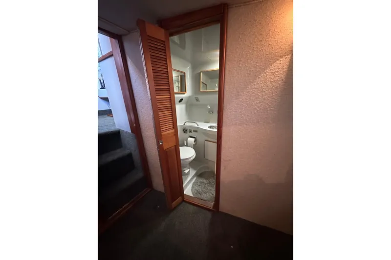 1990 Sea Ray 380 Aft Cabin bathroom with wooden door and compact design.