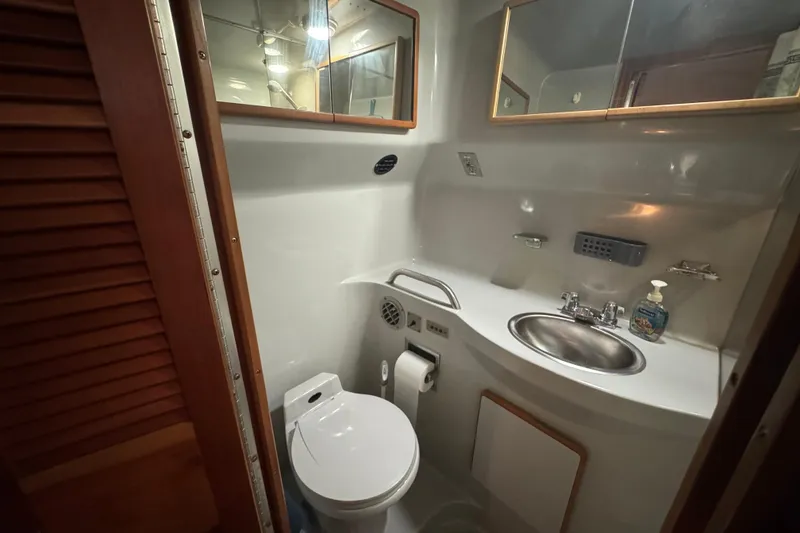 1990 Sea Ray 380 Aft Cabin bathroom with sink, toilet, and mirror.
