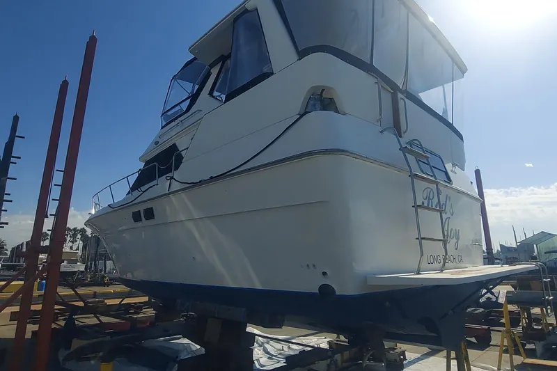 1990 Sea Ray 380 Aft Cabin yacht on dry dock under clear blue sky.