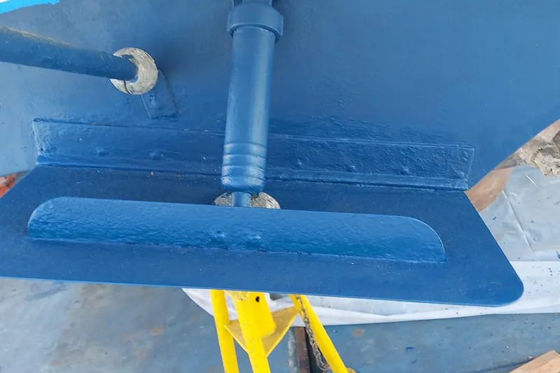 Close-up of a 1990 Sea Ray 380 Aft Cabin boat's blue-painted rudder and propeller shaft.