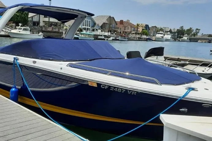 2018 Chaparral 267 SSX boat docked with blue cover in a marina setting.