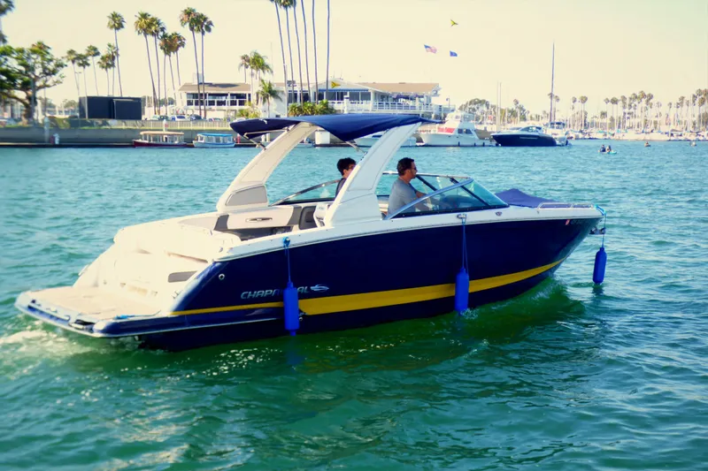 2018 Chaparral 267 SSX boat cruising in a sunny marina with palm trees.
