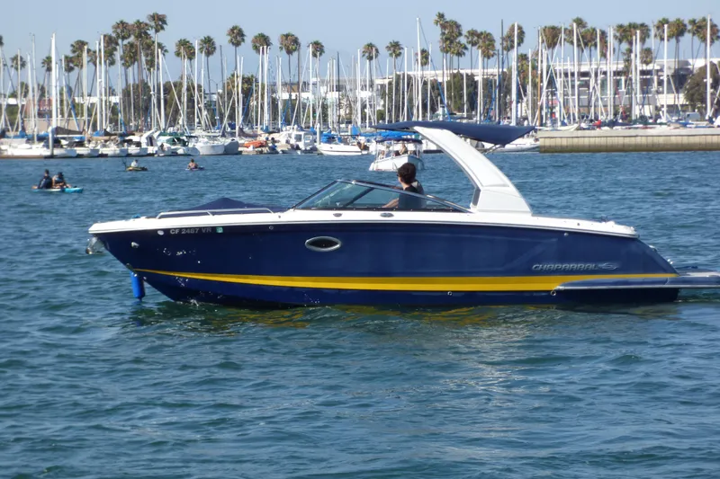 2018 Chaparral 267 SSX boat cruising in a marina with sailboats and palm trees.