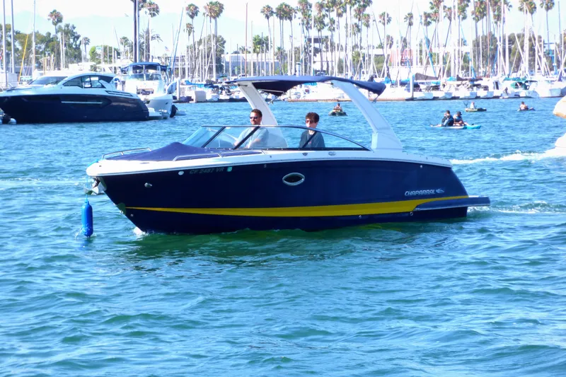 2018 Chaparral 267 SSX boat cruising in a marina with palm trees in the background.