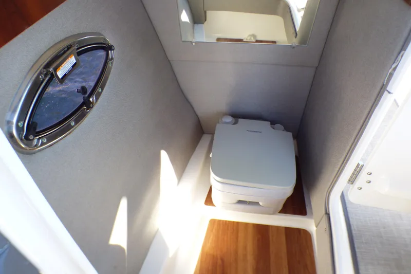 2018 Chaparral 267 SSX boat interior with compact marine toilet and porthole window.
