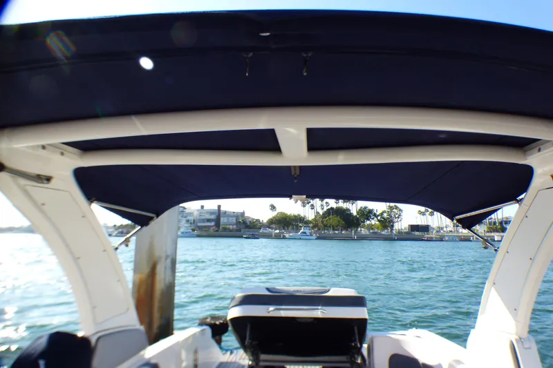 2018 Chaparral 267 SSX boat with canopy, docked near waterfront homes.