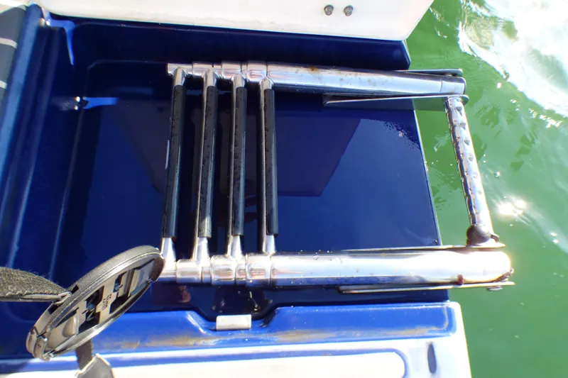 Stainless steel swim ladder on 2018 Chaparral 267 SSX boat, folded on blue platform.