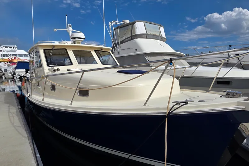 2005 Mainship 34 Pilot Sedan Rum Runner II docked at marina under blue sky.