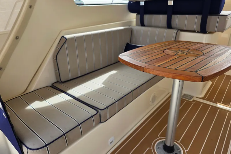 2005 Mainship 34 Pilot Sedan Rum Runner II interior with striped seating and wooden table.