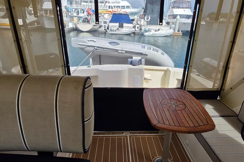 Interior view of 2005 Mainship 34 Pilot Sedan Rum Runner II, featuring seating and a wooden table.