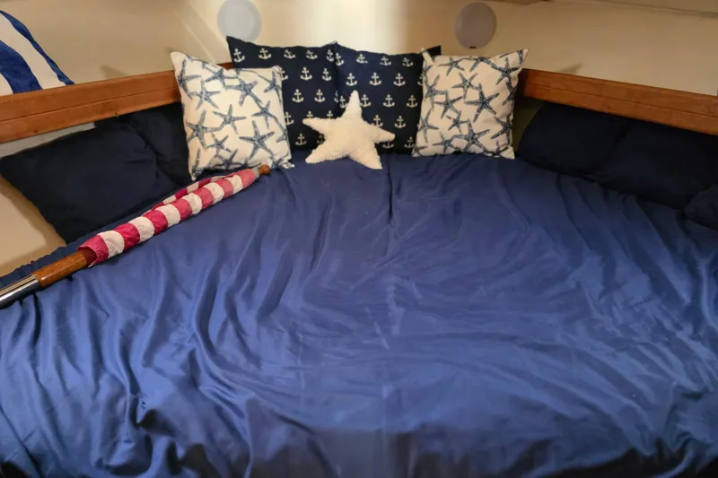 Cozy cabin interior of 2005 Mainship 34 Pilot Sedan Rum Runner II with nautical-themed pillows.