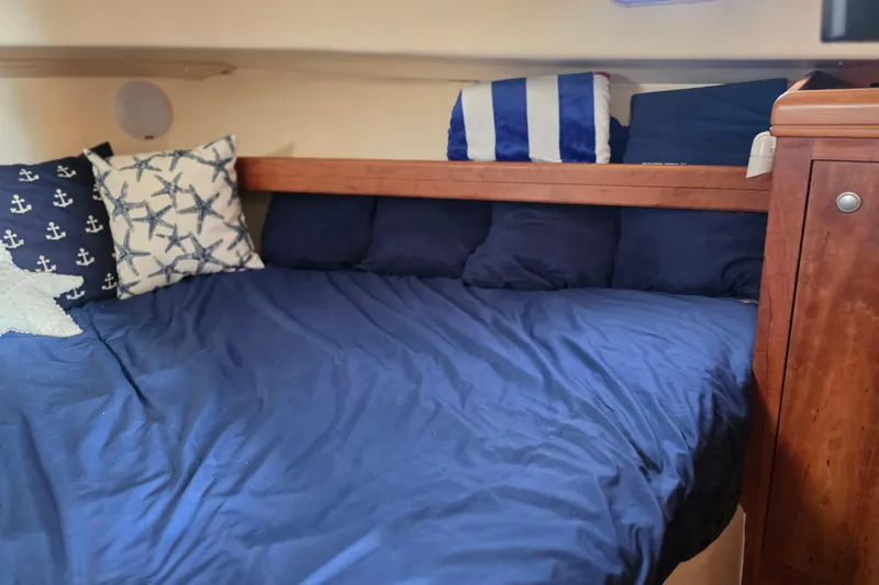 Cozy cabin bed with nautical-themed pillows on 2005 Mainship 34 Pilot Sedan Rum Runner II.