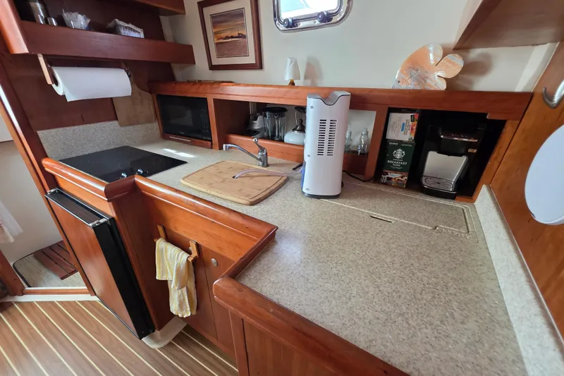 2005 Mainship 34 Pilot Sedan Rum Runner II galley with wooden cabinetry and modern appliances.
